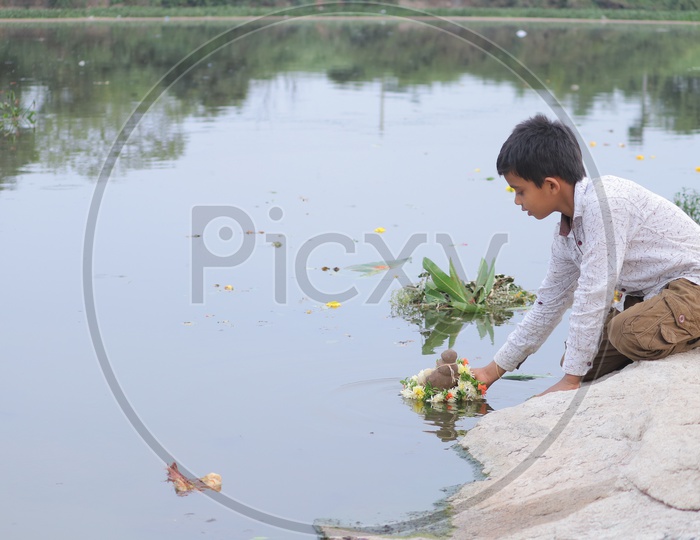 A young boy immersing mclay Ganesh Idol in the river