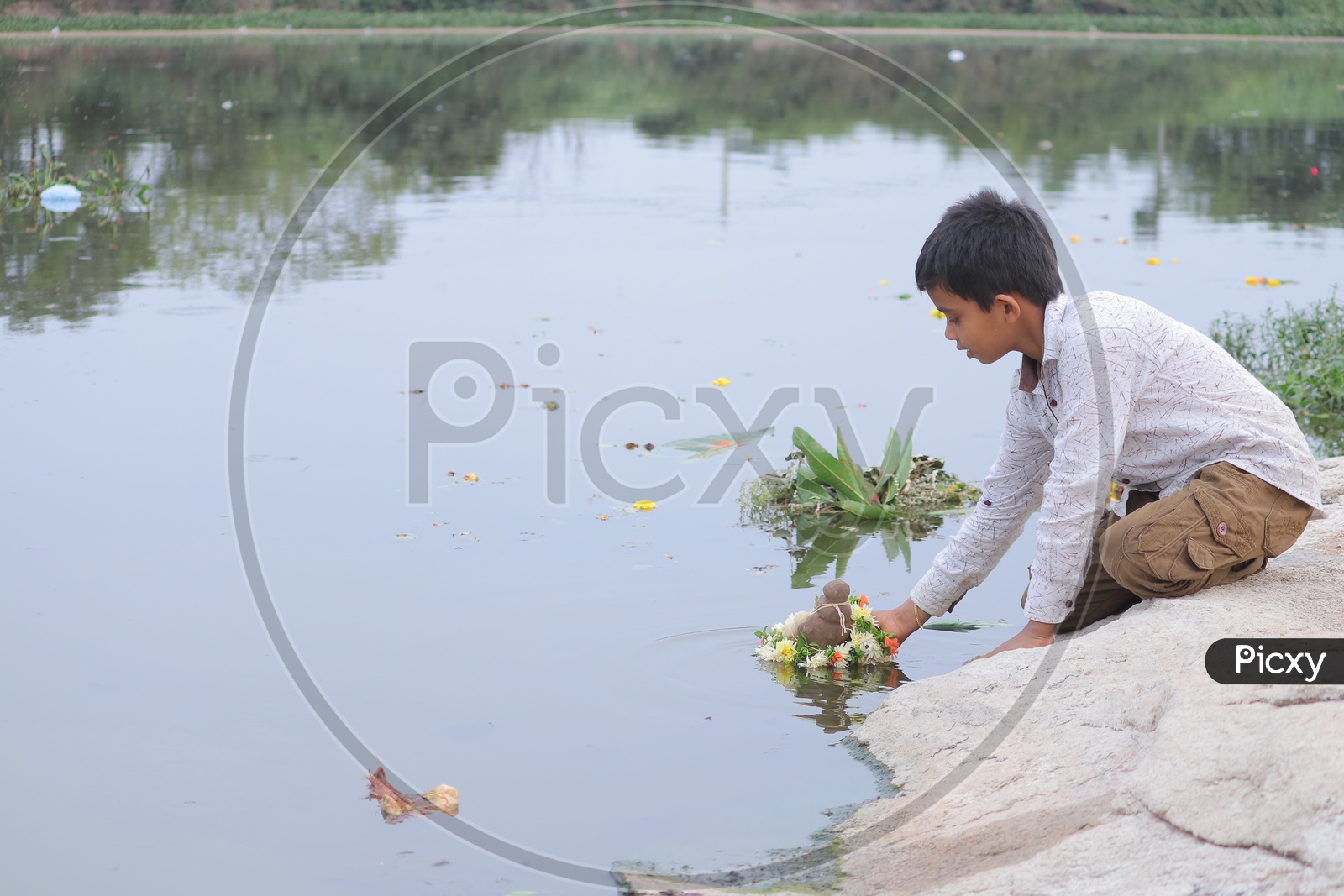 A young boy immersing mclay Ganesh Idol in the river