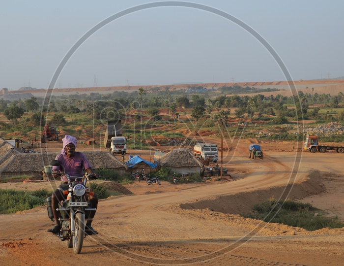 An old man driving a bike on a road at Kaleshwaram project