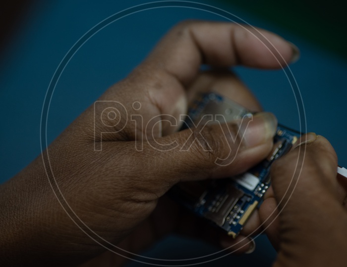 Technicians Assembling Manually The Micro  Parts In a Mobile Manufacturing Unit