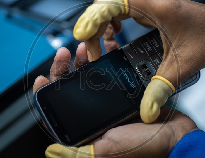 Technicians Manually Fitting the Mobile Phones in a Manufacturing Unit Hands Closeup Shots