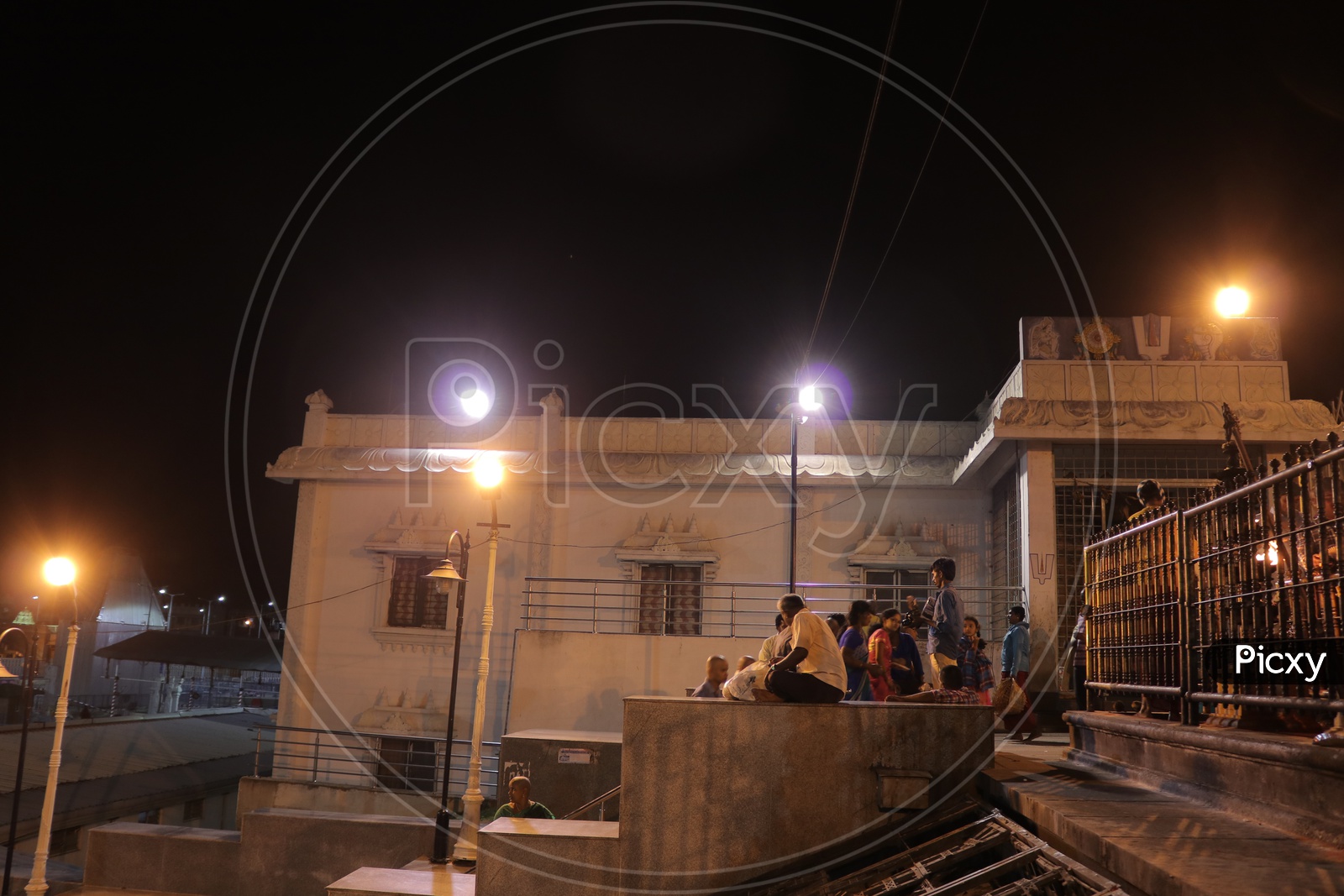 People sitting on a cement block in a temple during night