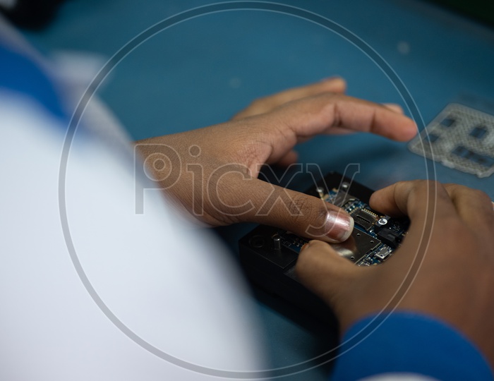 Technicians Assembling Mobile Parts Manually  In a Mobile Manufacturing Unit