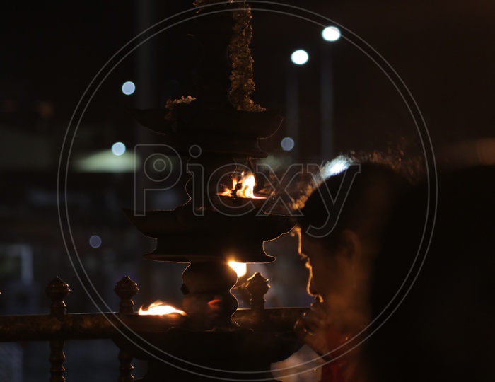 Devotee praying in front of aarti in a temple