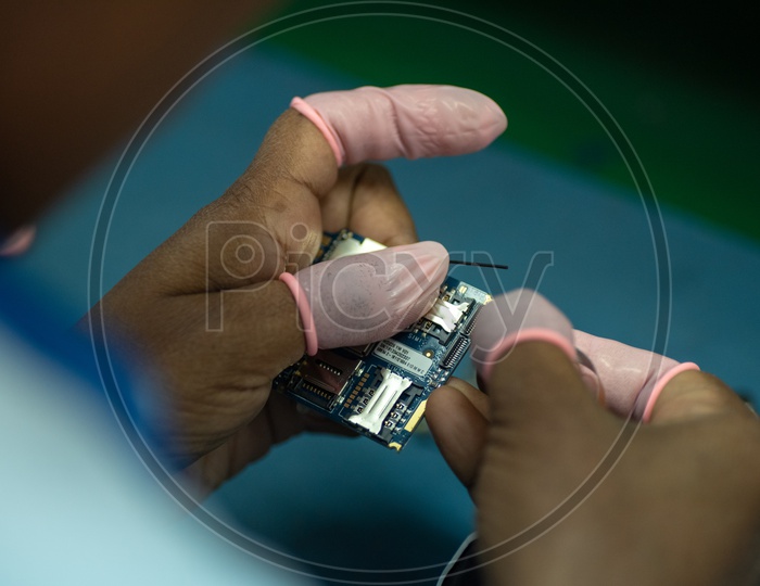 Technicians Assembling Micro Parts of Phones In a Manufacturing Unit