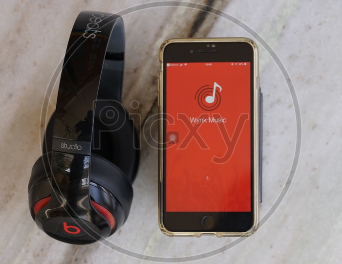 Flat lay of headphone and smart phone with Wynk app icon on screen