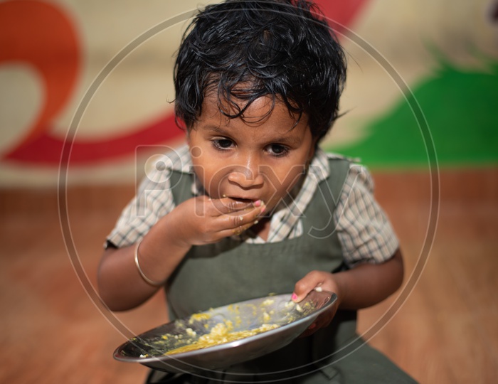 A girl student eating her mid day meal in an Anganwadi center