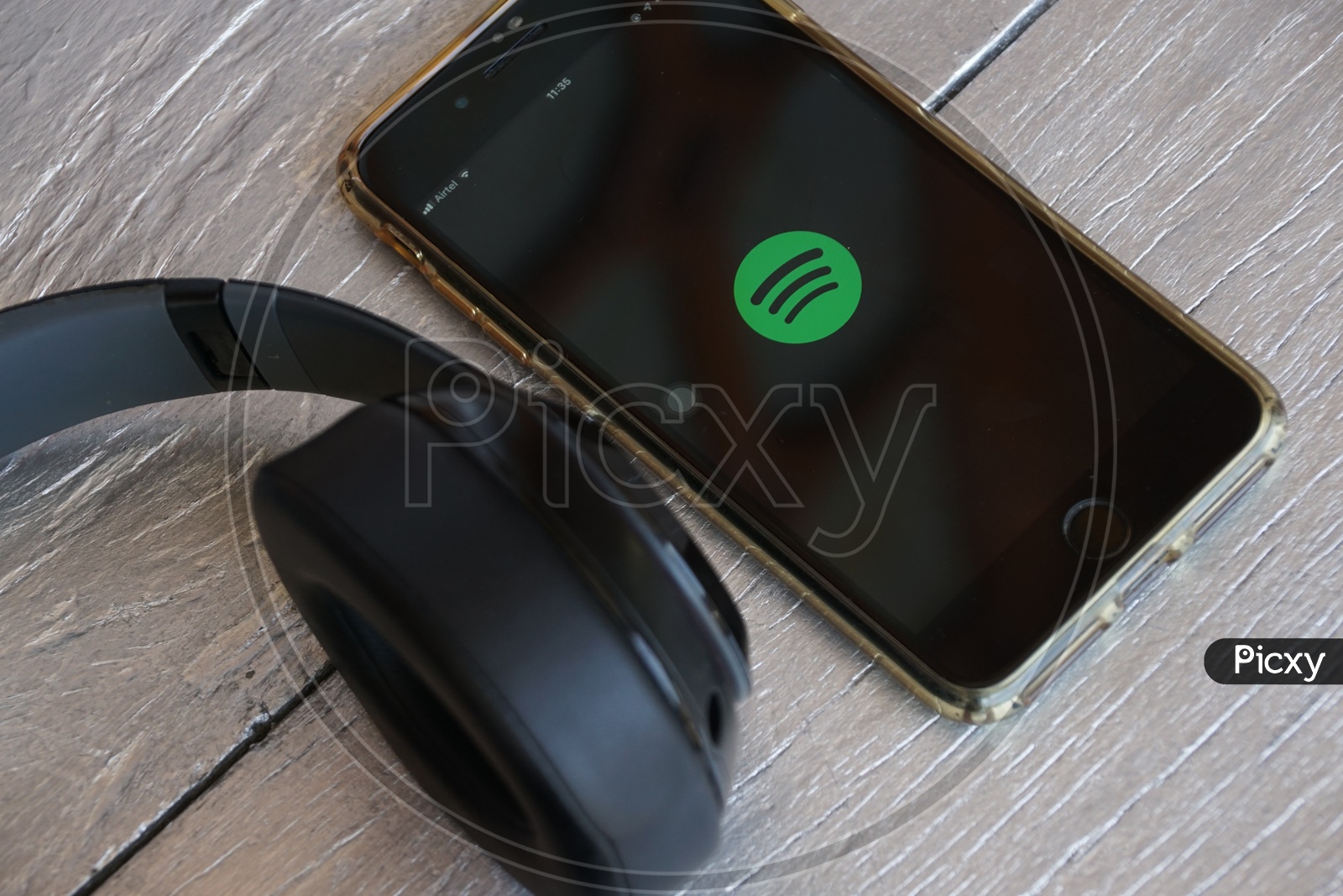 Flat lay of headphone and smart phone with Spotify app icon on screen