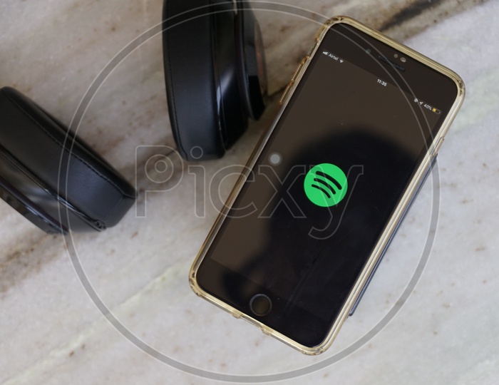 Flat lay of headphone and smartphone with Spotify app icon on screen