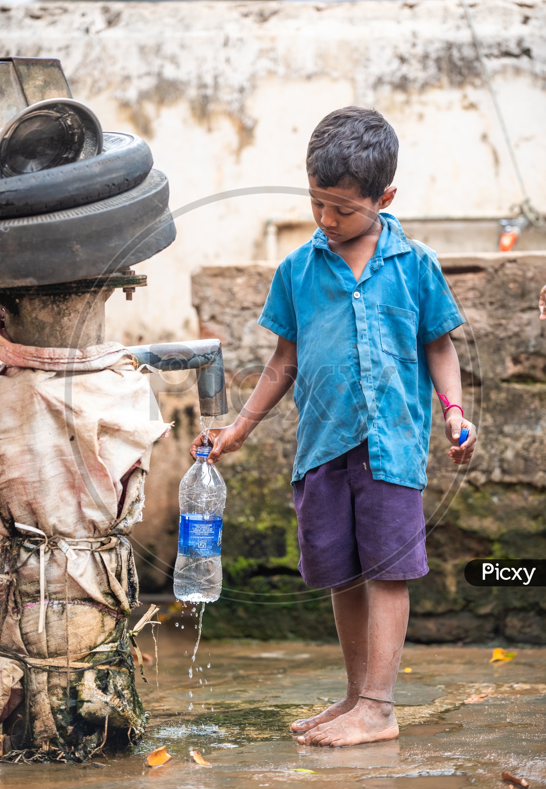 A primary school student filling his water bottle near a hand pump