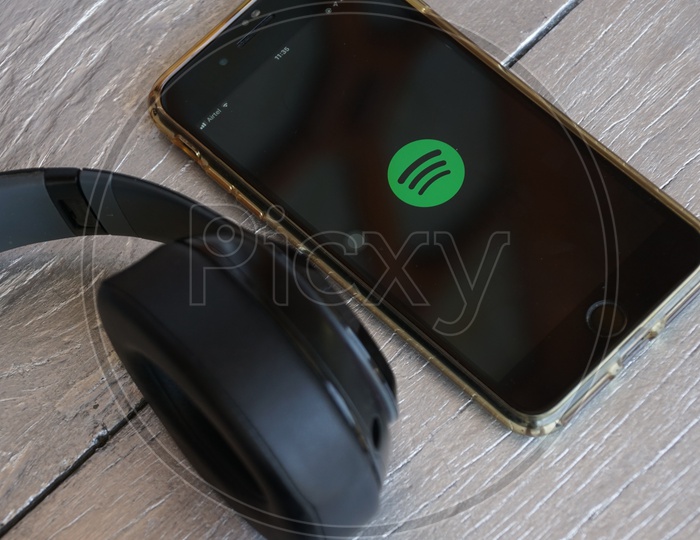 Flat lay of headphone and smart phone with Spotify app icon on screen
