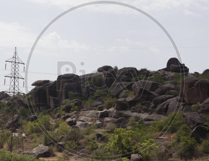 large rocks in a open area with electricity lines passing beside it