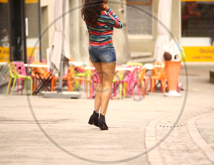 A girl in colorful striped tee and shorts walking on the road