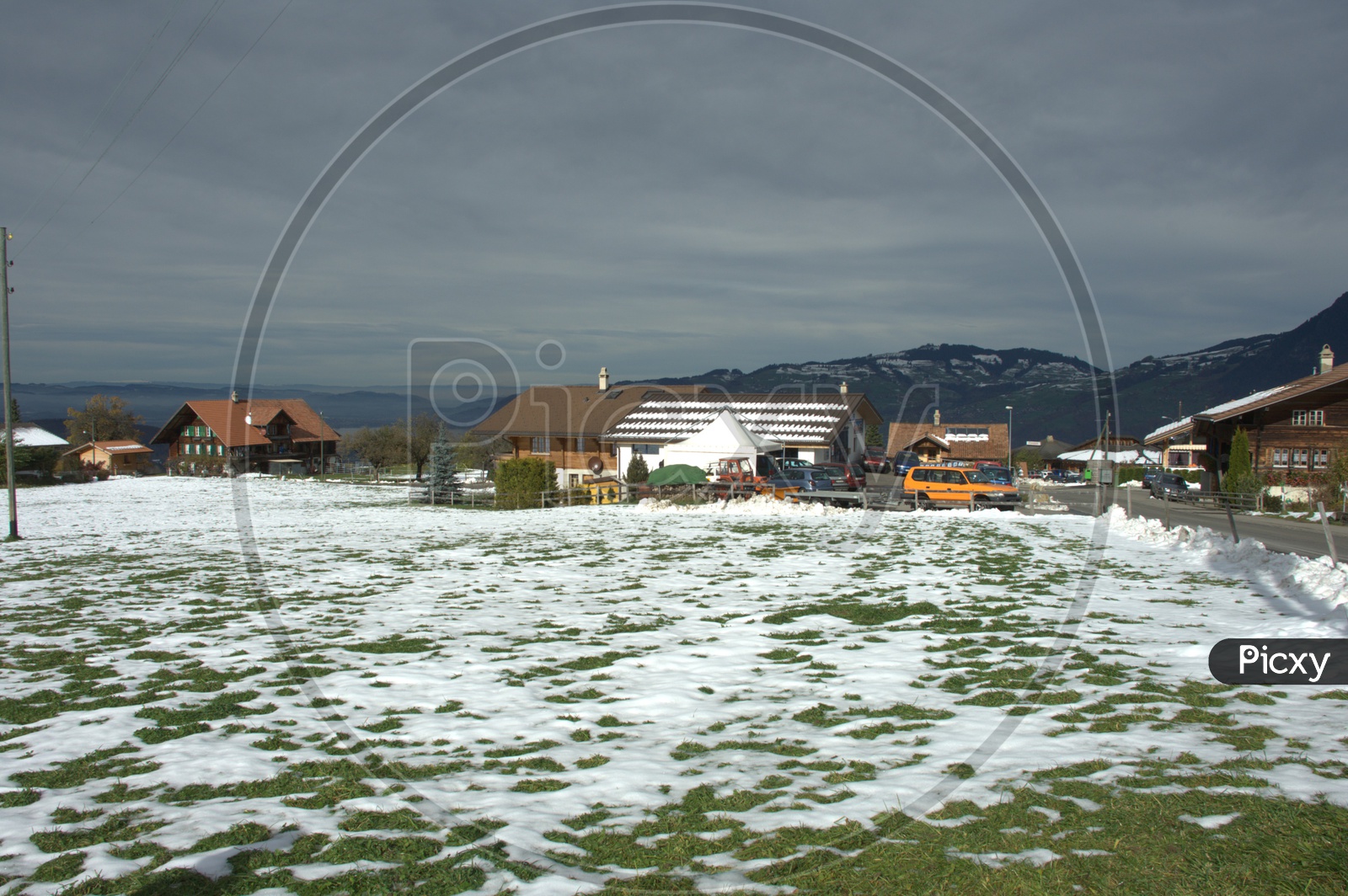 Snow on the grass alongside the wooden houses