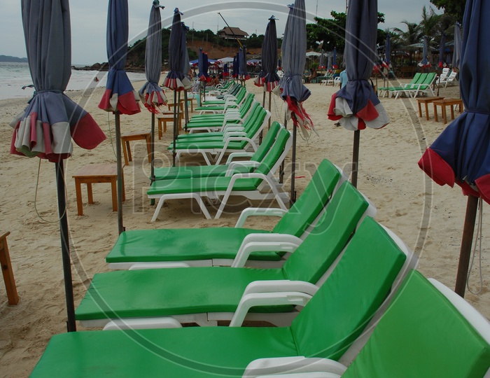 Beach beds and closed umbrellas alongside the shore