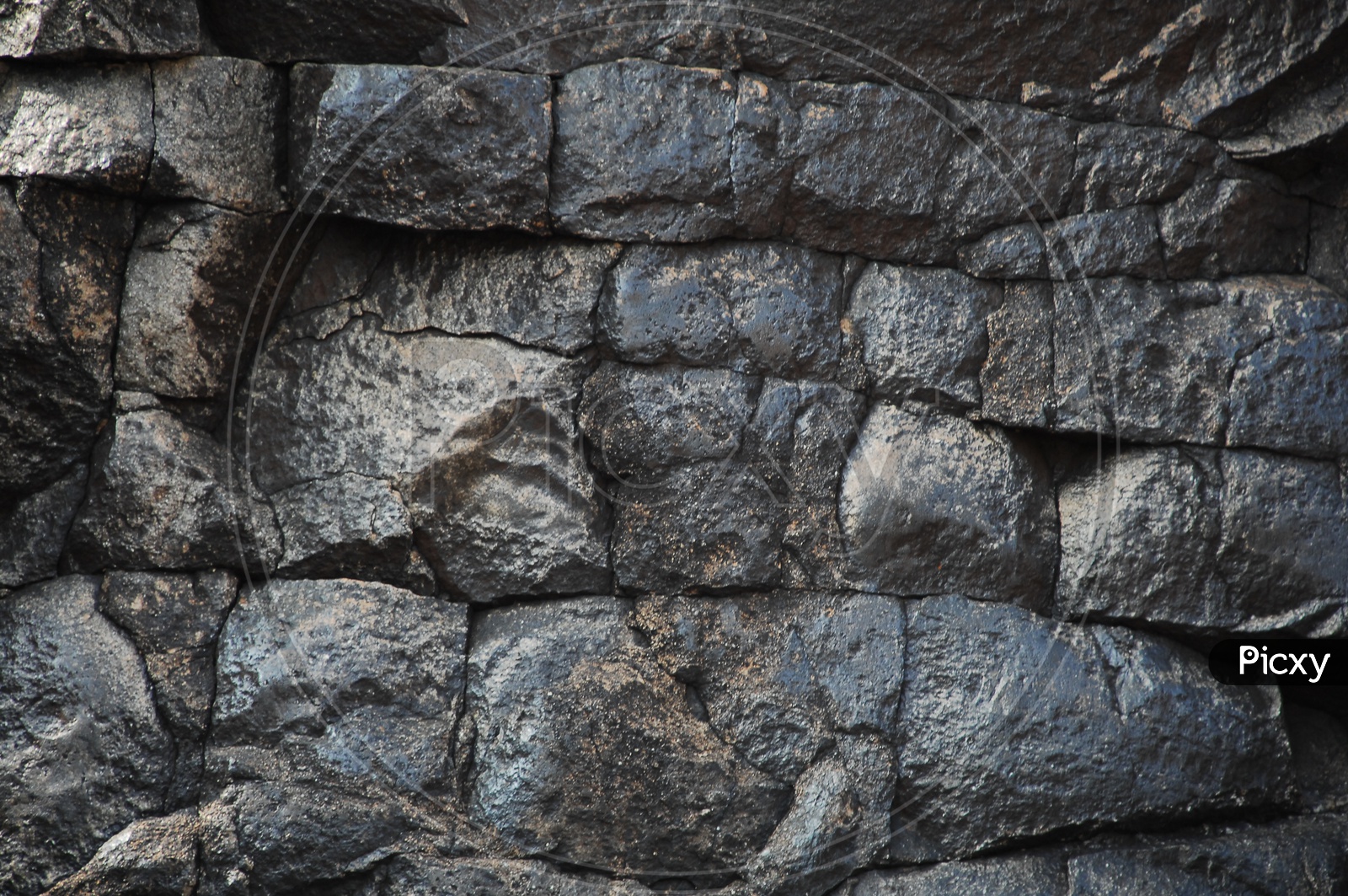 Wall built with large black rocks
