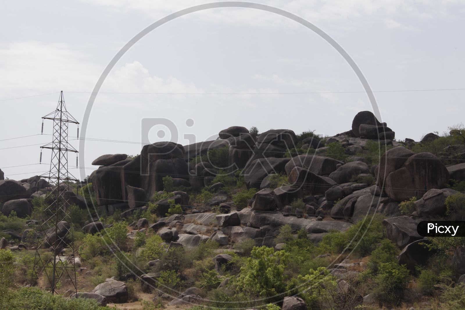large rocks in a open area with electricity lines passing beside it