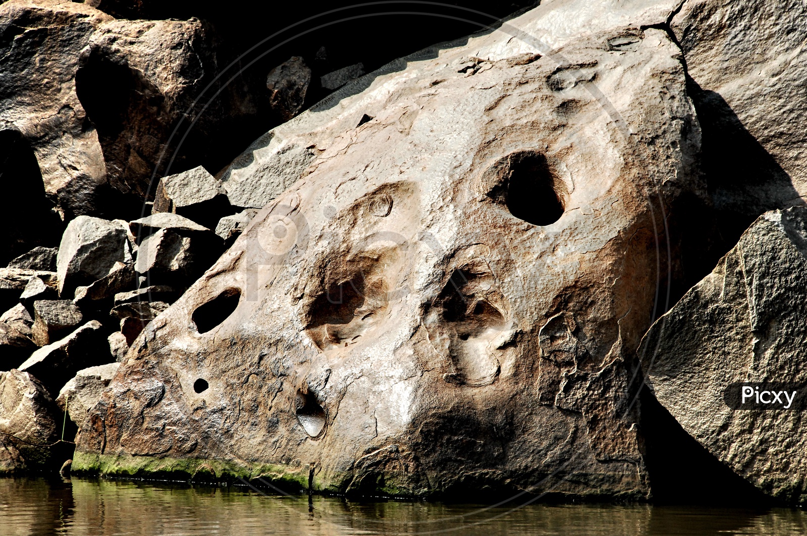 A rock with holes beside a lake