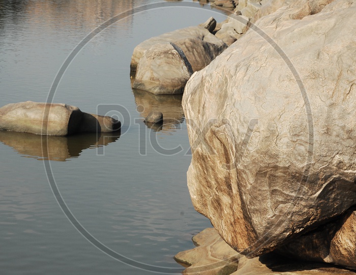 Large rocks inside and beside a lake