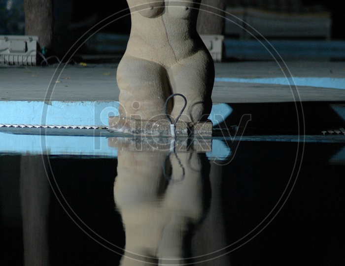 A stone carving of a woman alongside the pool