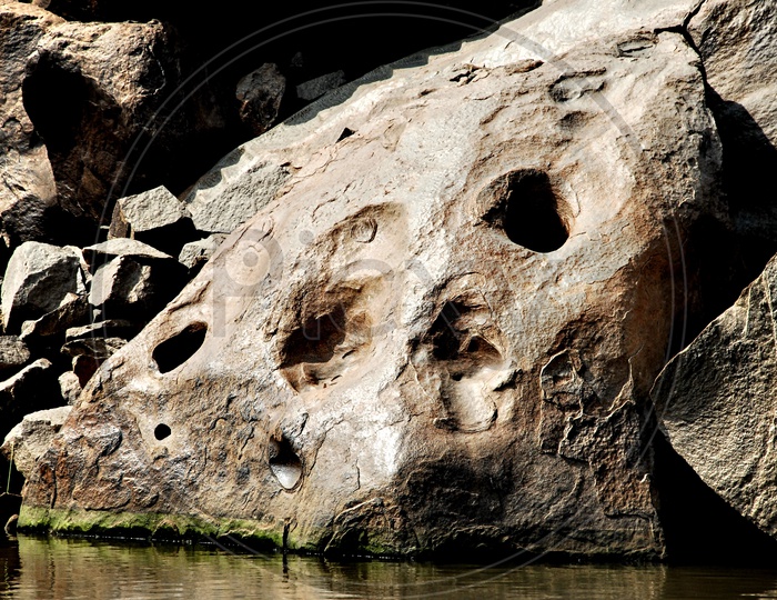 A rock with holes beside a lake