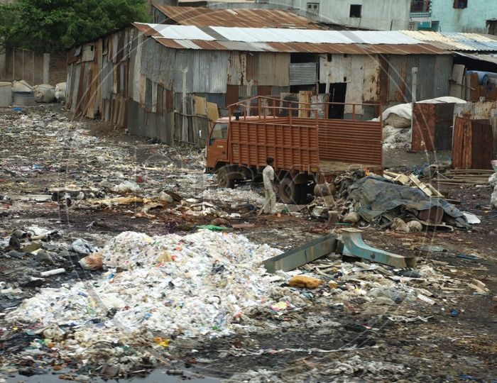 Garbage Dumped At Slum Area With Steel Sheet Huts Present