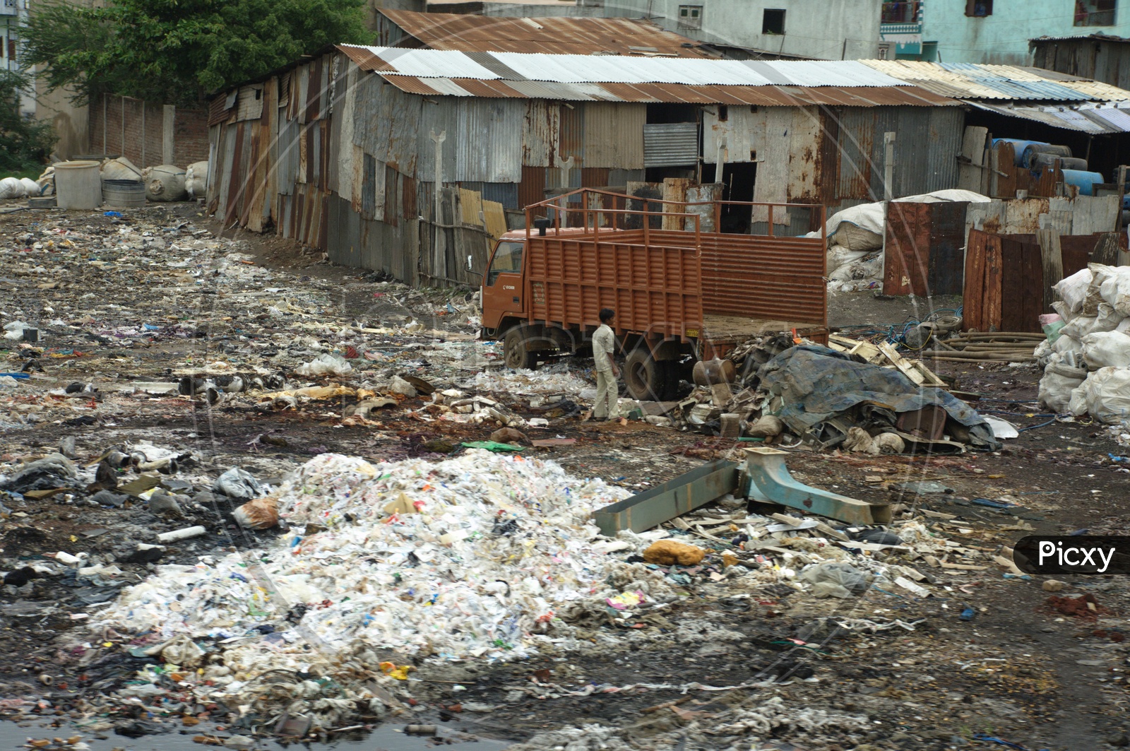 Garbage Dumped At Slum Area With Steel Sheet Huts Present
