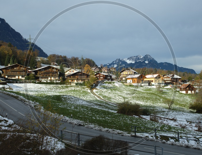 Grassland covered with partial snow alongside the wooden houses