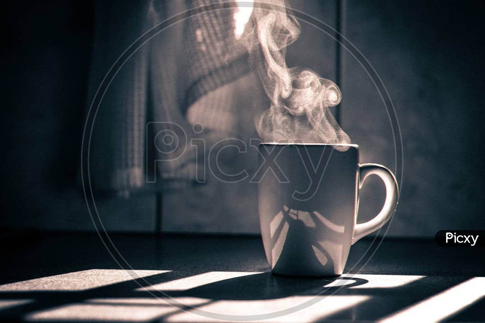 A coffee mug with smoke coming out of it and sunlight in the backdrop