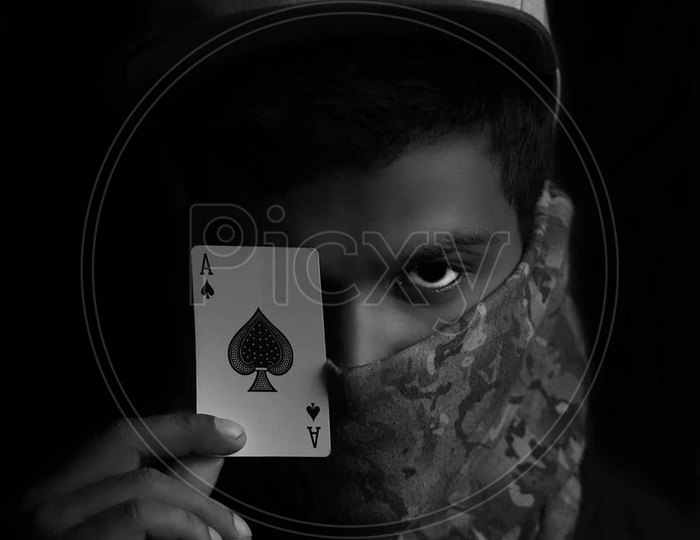 portrait of a person with mask,cap and with solitaire card in the hand