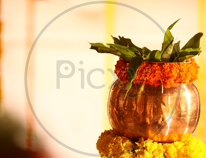Brass bowl decorated with marigold flowers and mango leaves