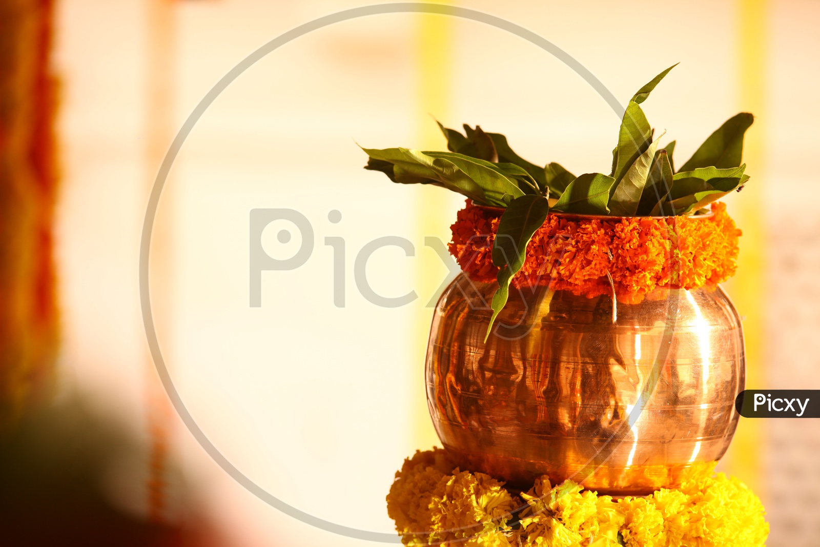 Brass bowl decorated with marigold flowers and mango leaves
