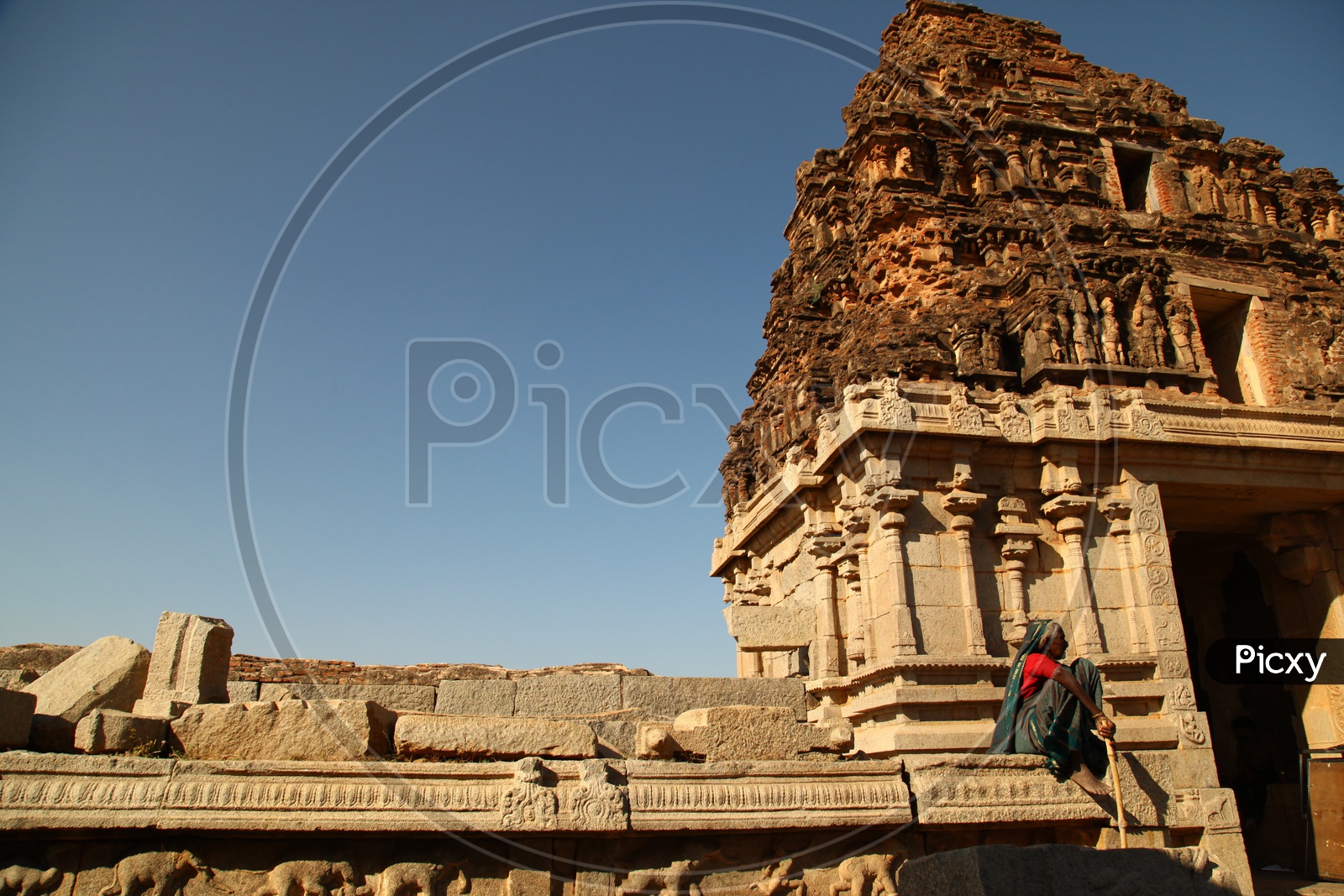 An old woman sitting on the ancient ruins of the temple