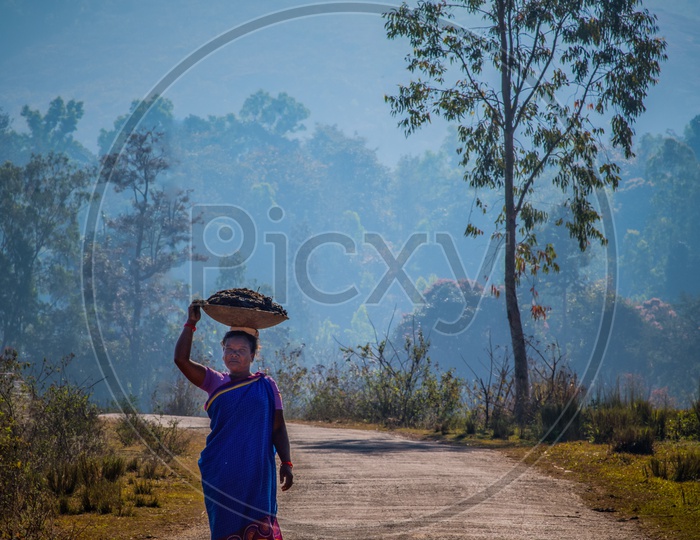 A Tribal Woman Carrying a Basket On Her Head on a Road