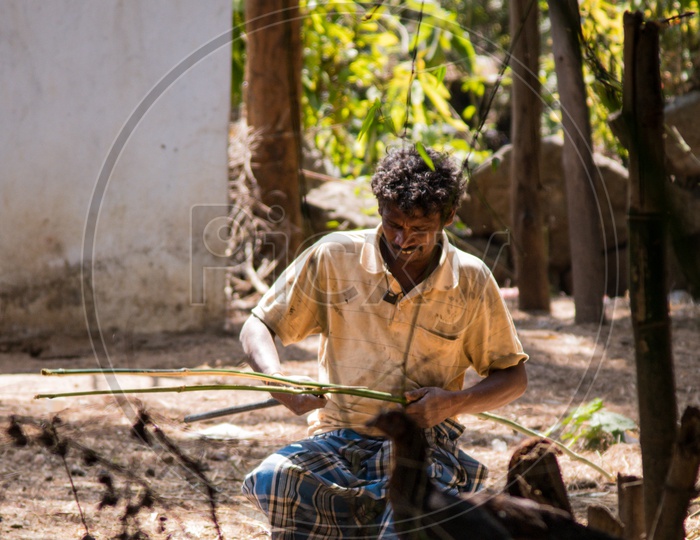 A Man Slicing The Bamboo Sticks For Weaving Baskets