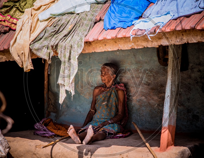 An Old Woman Sitting Under a Hut Roof In Rural Tribal Village