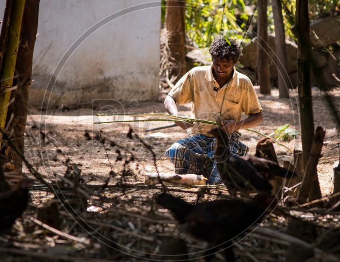 A Tribal Man Slicing Bamboo Sticks For Weaving Baskets