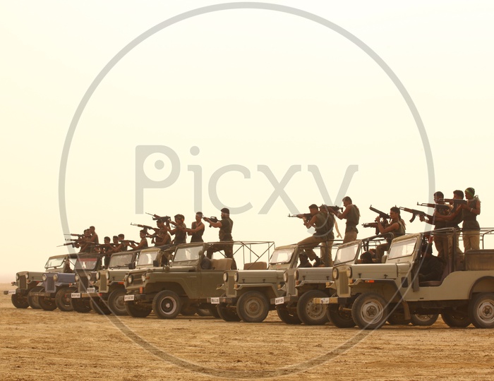 group of people with guns on the vehicles in a desert,  bandits