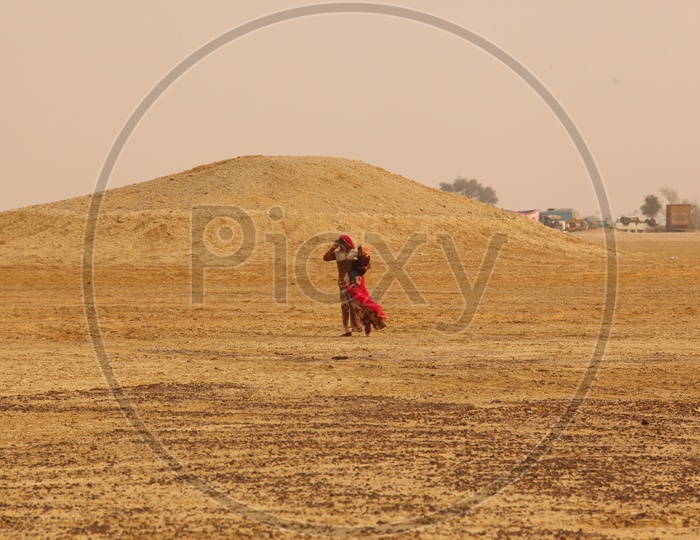 Indian old woman walking in a desert