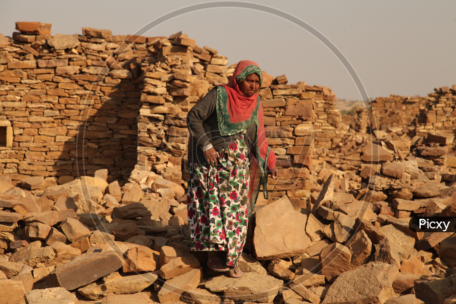 Indian Old woman walking alongside the old ruins