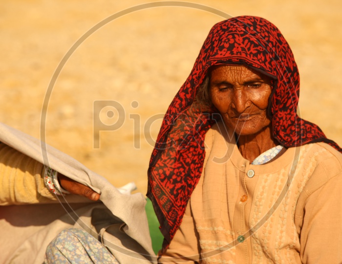 A old rajasthani women seated in the desert