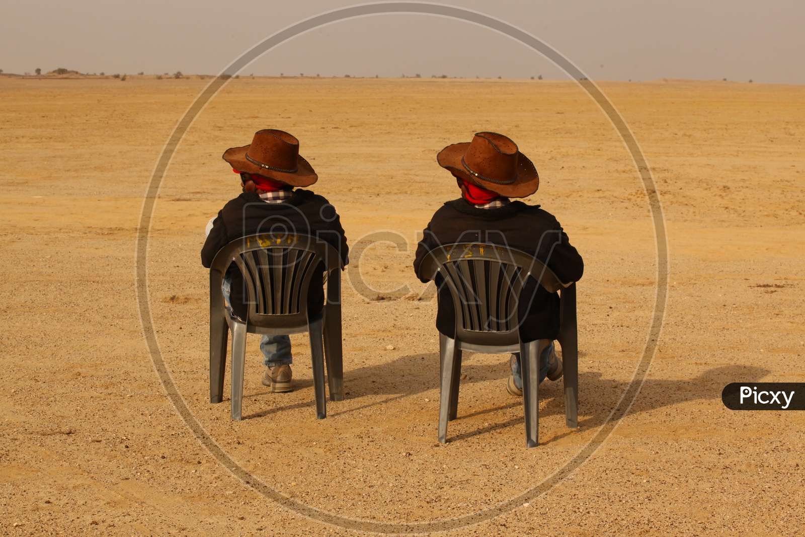 Image of Two men with hats sitting in the chairs at a desert-IK179478-Picxy