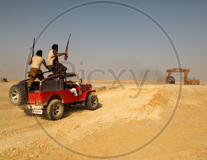 people with guns moving in vehicles in a desert