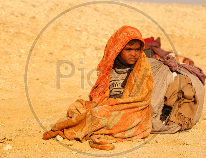 A kid covered with blanket in the desert