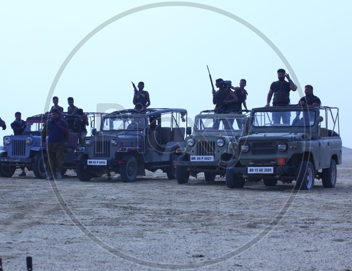 People with guns on the vehicles in a desert, bandits