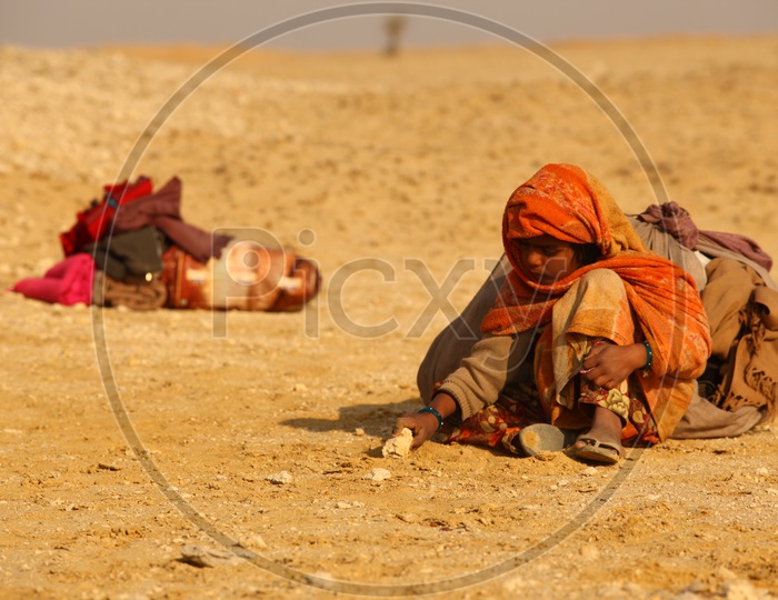 A kid playing with stones in the desert