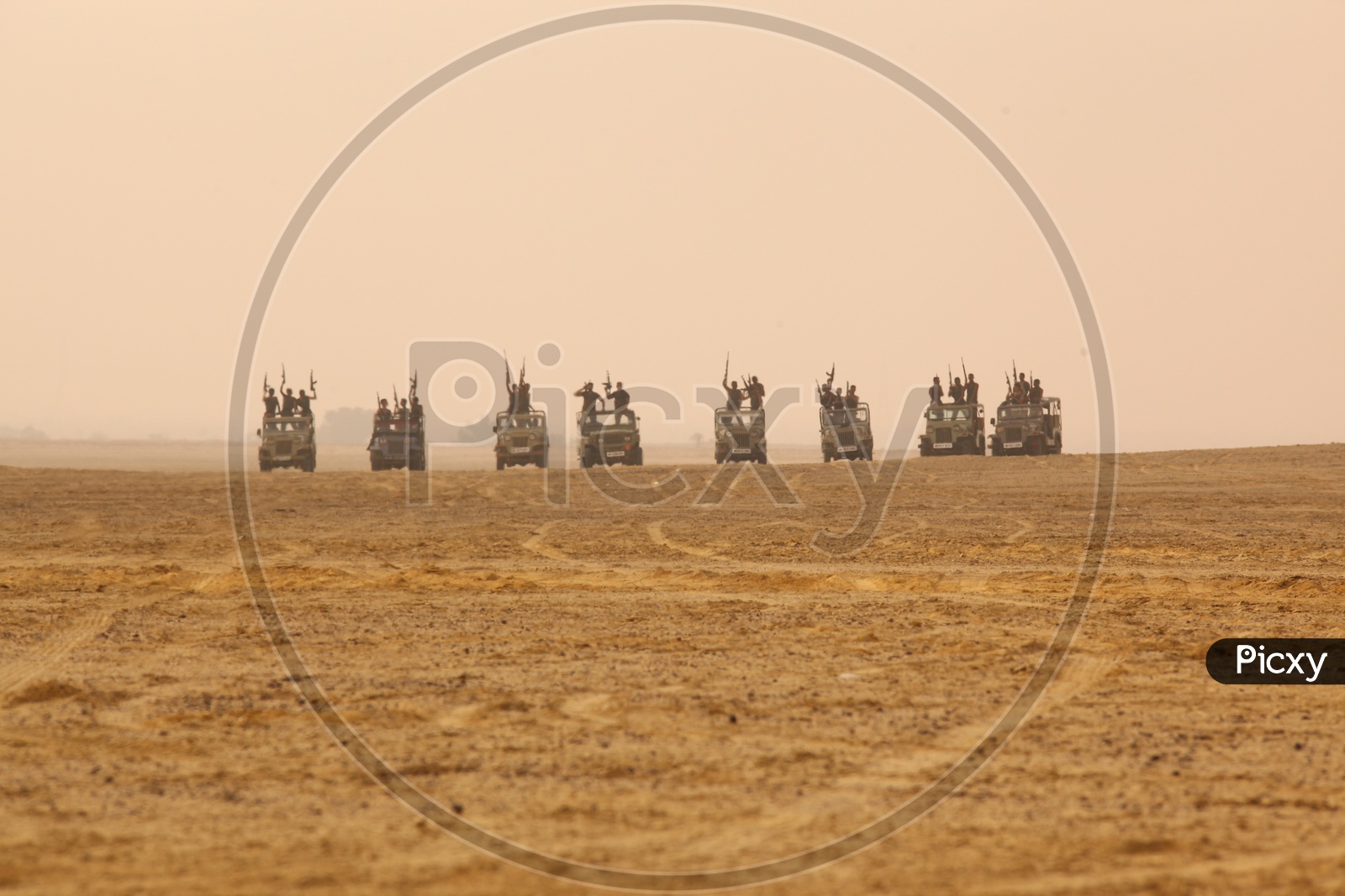 group of people with guns on the vehicles in a desert, bandits