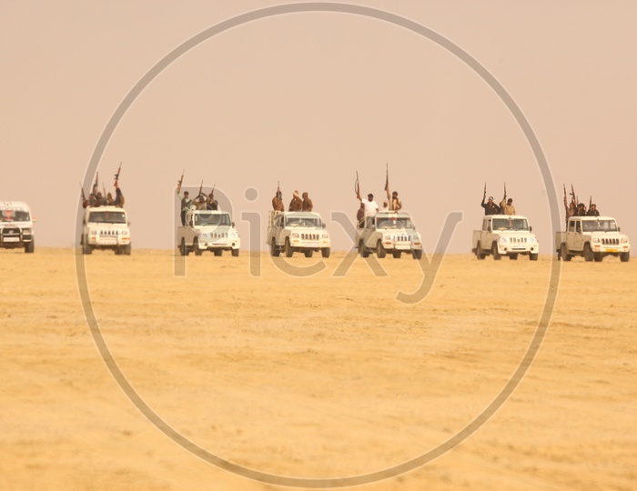 group of vehicles and people with guns in the desert