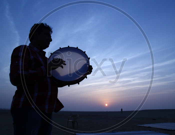 Silhouette of a man playing kanjira