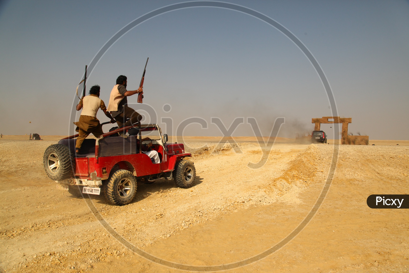 people with guns moving in vehicles in a desert